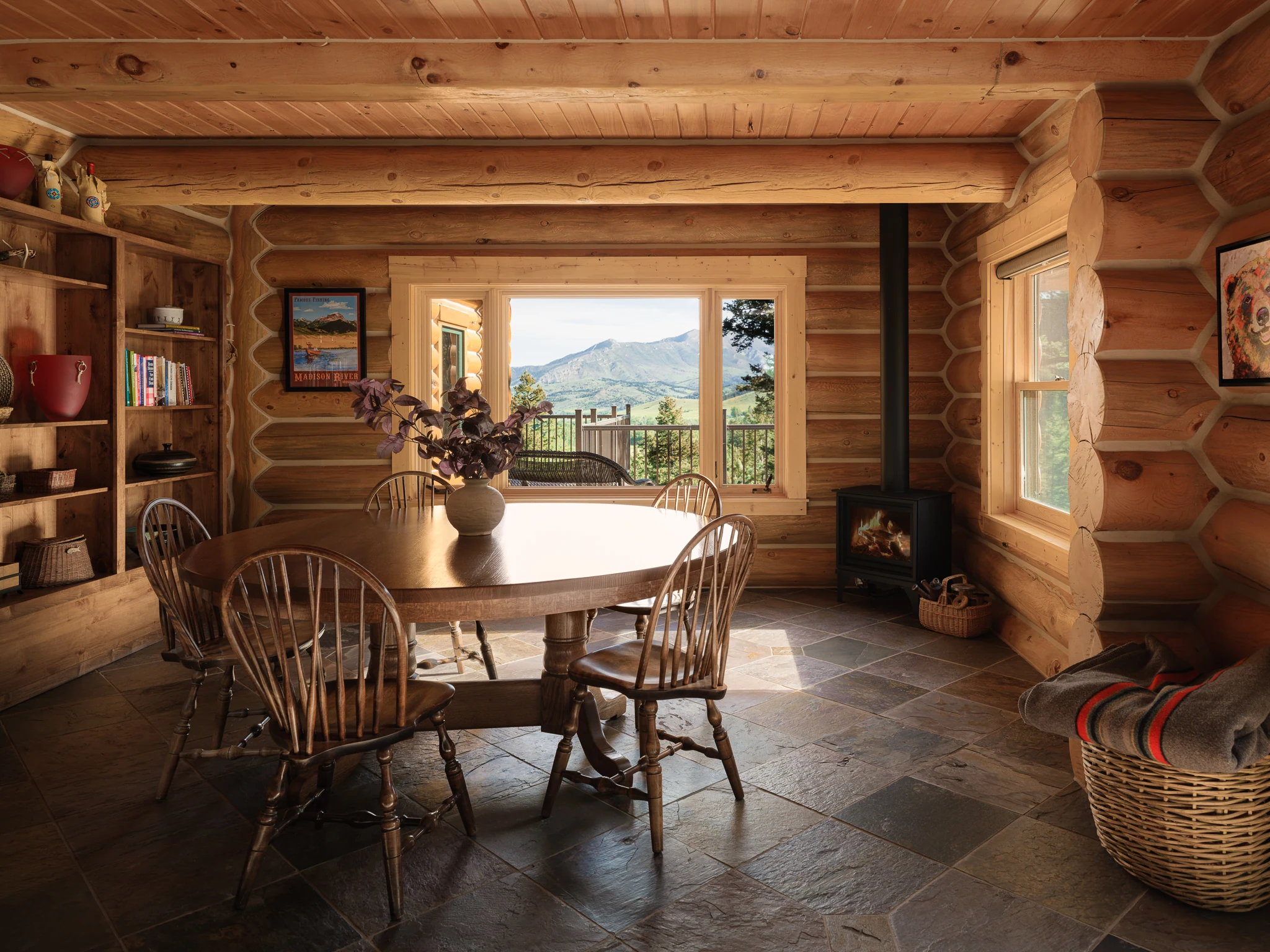 Dining nook with round wood table and mountain view through a picture window — interior design photography Livingston Montana, Sam Schlauch Designs